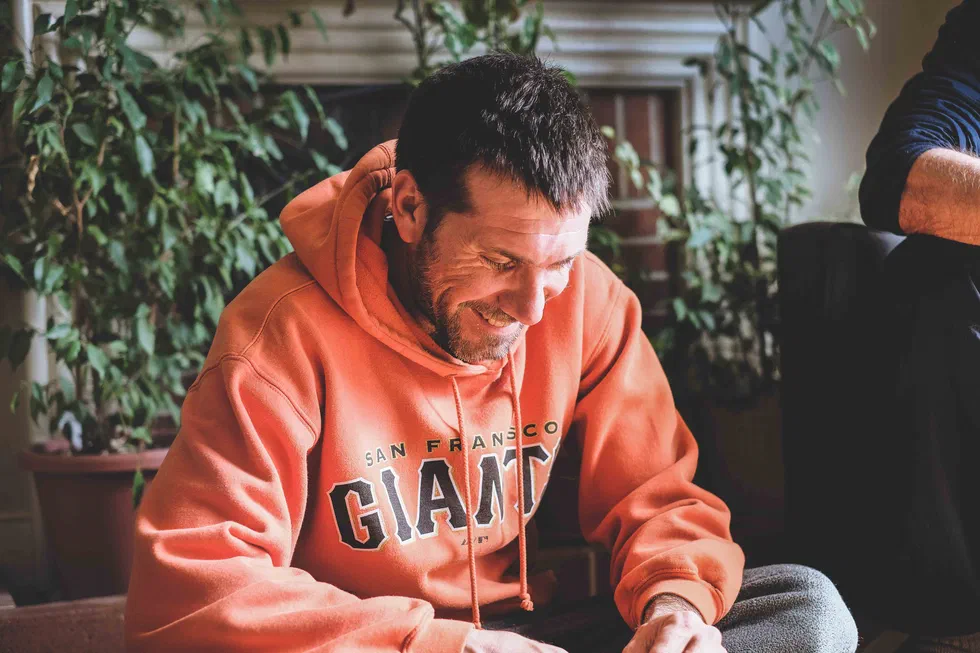 Homme souriant en sweat orange assis en intérieur