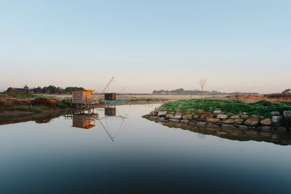 Cabane de carrelet et chenal paisible à l’aube