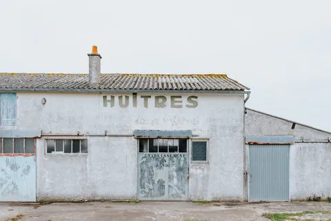 Façade d&rsquo;un ancien bâtiment ostréicole avec l&rsquo;enseigne Huitres