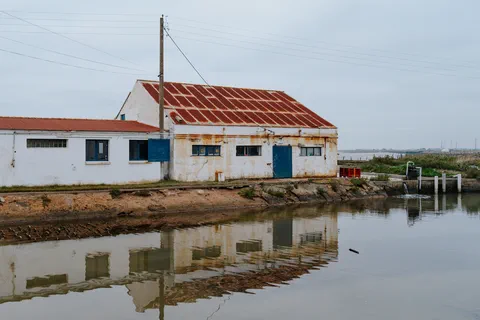 Bâtiment ostréicole au bord d&rsquo;un canal sous un ciel gris