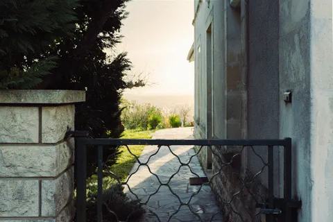 House path bordered by a metal gate in soft light