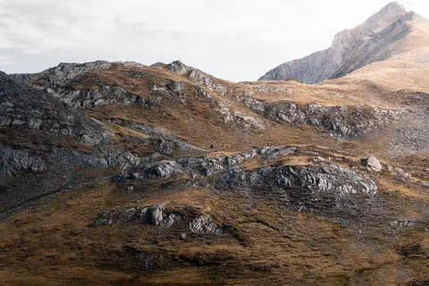 Une photo de la montagne avec un randonneur en sont centre. 