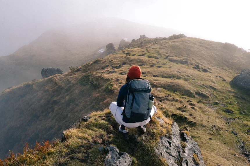 Randonneuse avec son sac à dos assise sur une crête rocheuse au Pic d’Escurets