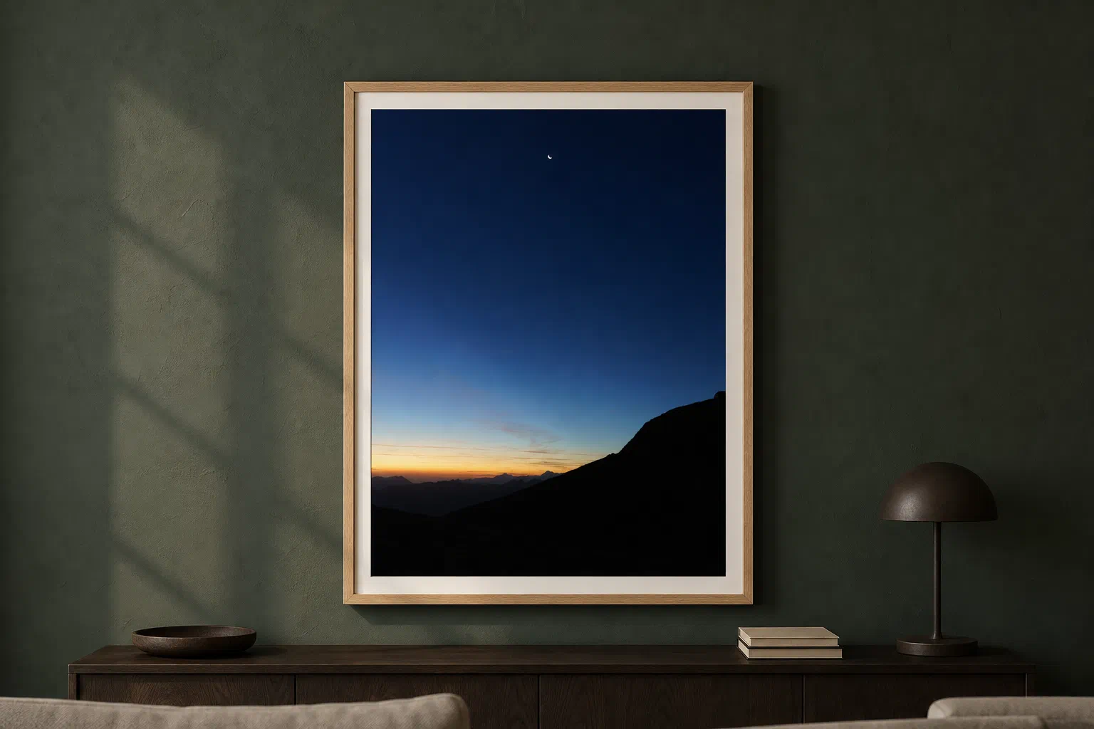 Croissant de lune à l'aube présenté dans un cadre en chêne sur un mur vert sombre